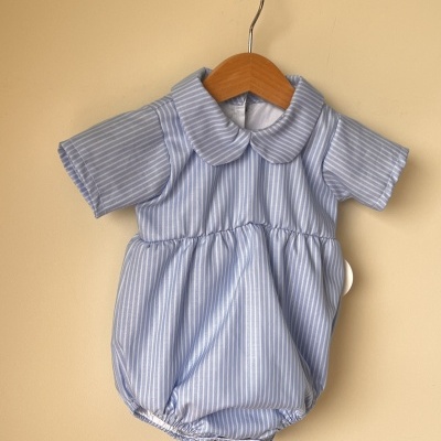 Roupa de bebé azul claro às riscas brancas pendurada num cabide de madeira