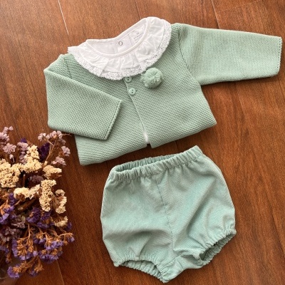 Conjunto de roupa de bebé verde com casaco e calções em madeira.
