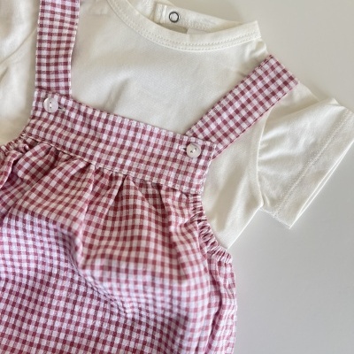 Conjunto infantil de camisola branca e vestido xadrez vermelho e branco sobre fundo branco