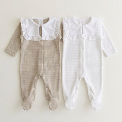 Dois macacões de bebé bege e branco com gola branca rendada e botões