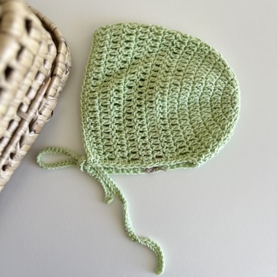 Touca de croché verde clara para bebé com cordão de amarração.