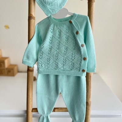 Conjunto de bebé em lã azul claro com casaco, calças e gorro pendurado em estrutura de madeira