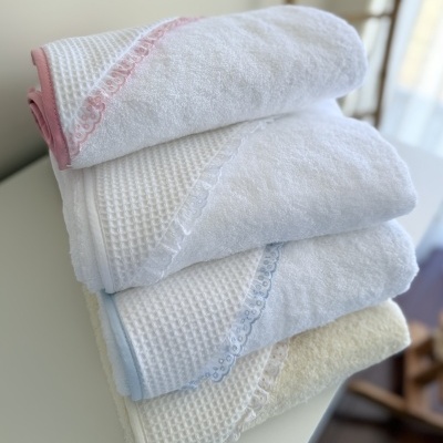 Conjunto de quatro toalhas de banho de algodão com bordas decorativas em cores suaves empilhadas