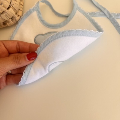 Babete de bebé branco com bordas azuis e padrão de nuvem azul claro