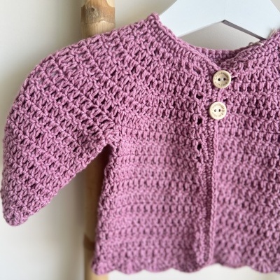 Casaco de tricô cor-de-rosa com botões em madeira pendurado