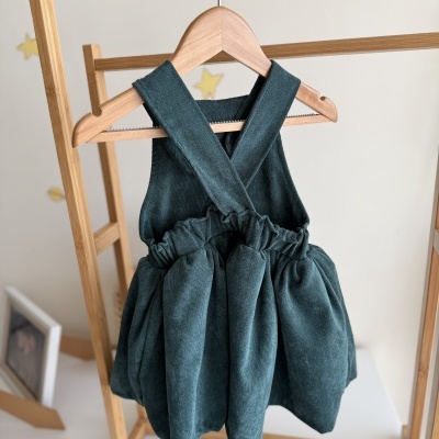 Vestido verde veludo com alças cruzadas pendurado em cabide de madeira