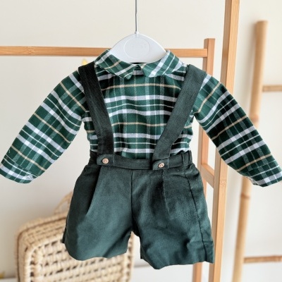 Conjunto de roupa de bebé verde e xadrez com calções de veludo pendurado num cabide