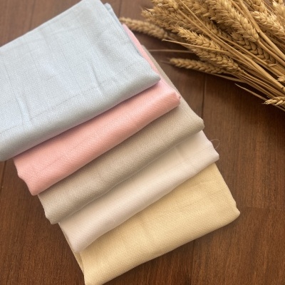 Tecidos dobrados em várias cores empilhados ao lado de ramo de espigas secas