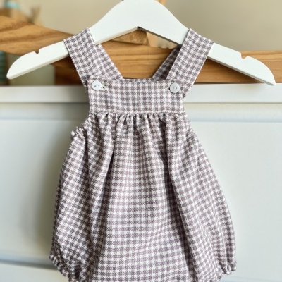 Romper de bebé em tecido xadrez bege e branco com alças e botões brancos