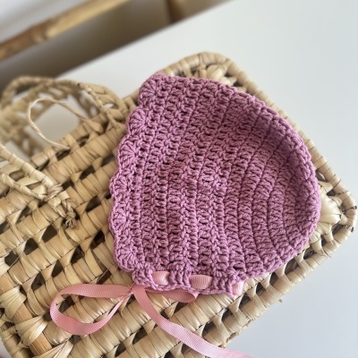 Gorro cor-de-rosa claro de croché sobre cesta de palha clara