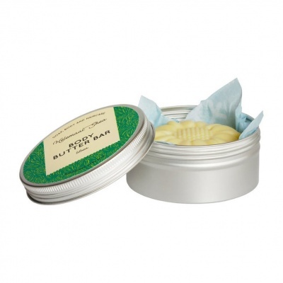 Barra de manteiga corporal amarela em lata metálica prateável com tampa aberta.