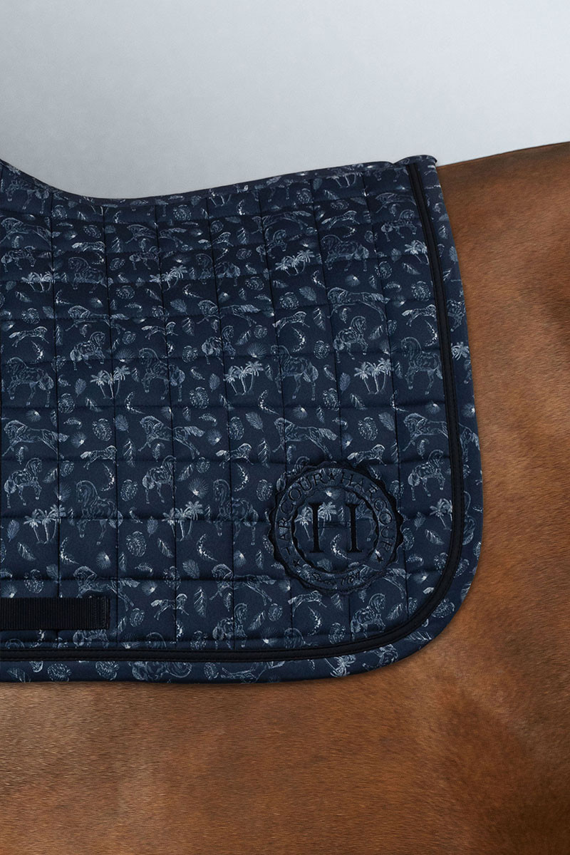 Suadouro HARCOUR "Sola" SS24 Mantilha azul escura acolchoada com padrão de folhas e bordado, colocada sobre cavalo castanho