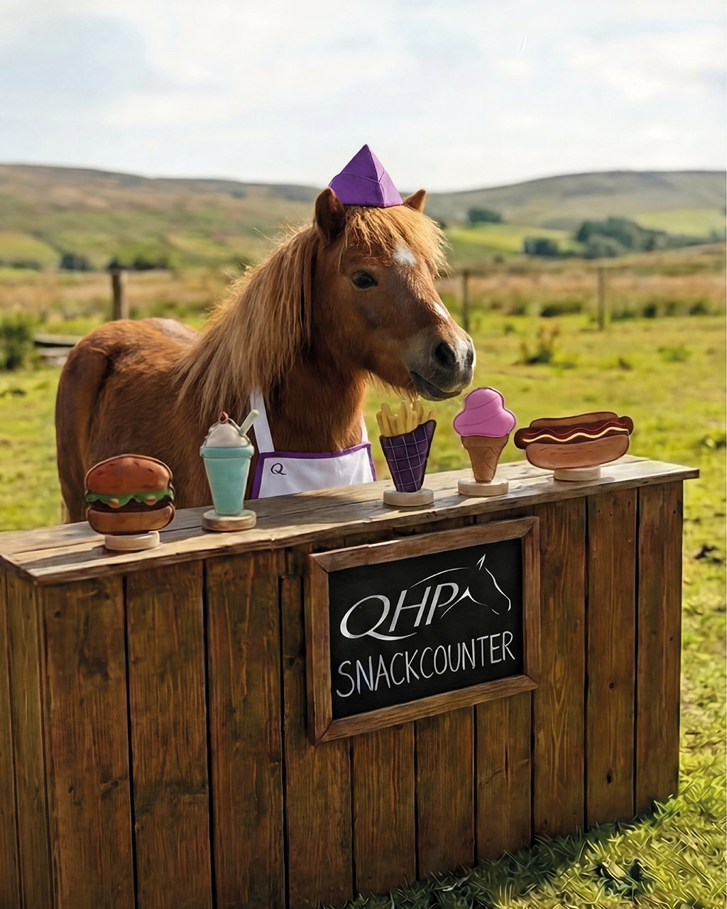 Brinquedo p/ Cavalo QHP Snackcounter Cavalo vestido com chapéu e avental roxos atrás de balcão de madeira com placa QHPA SNACKCOUNTER e réplicas coloridas de comida