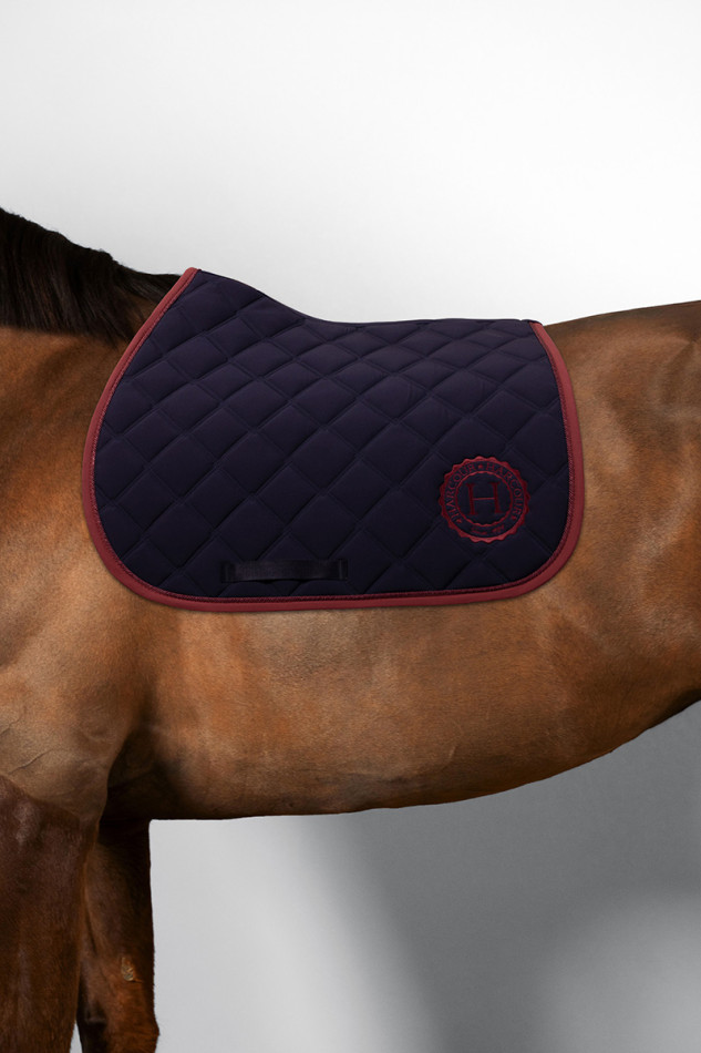 Suadouro HARCOUR Chimene Tapete de sela acolchoado azul escuro com rebordo grená e logótipo H vermelho em cavalo castanho