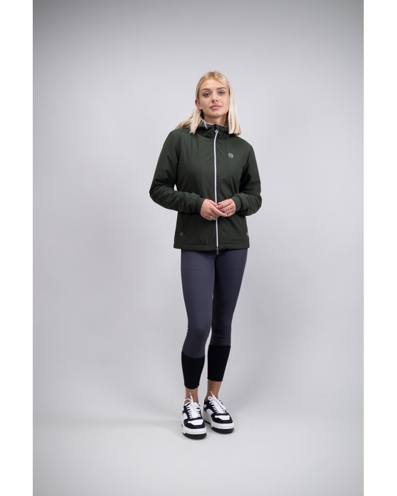 Casaco de Senhora HARCOUR "Simhat" Mulher com casaco verde escuro, leggings cinza e ténis brancos e pretos, fundo cinza claro