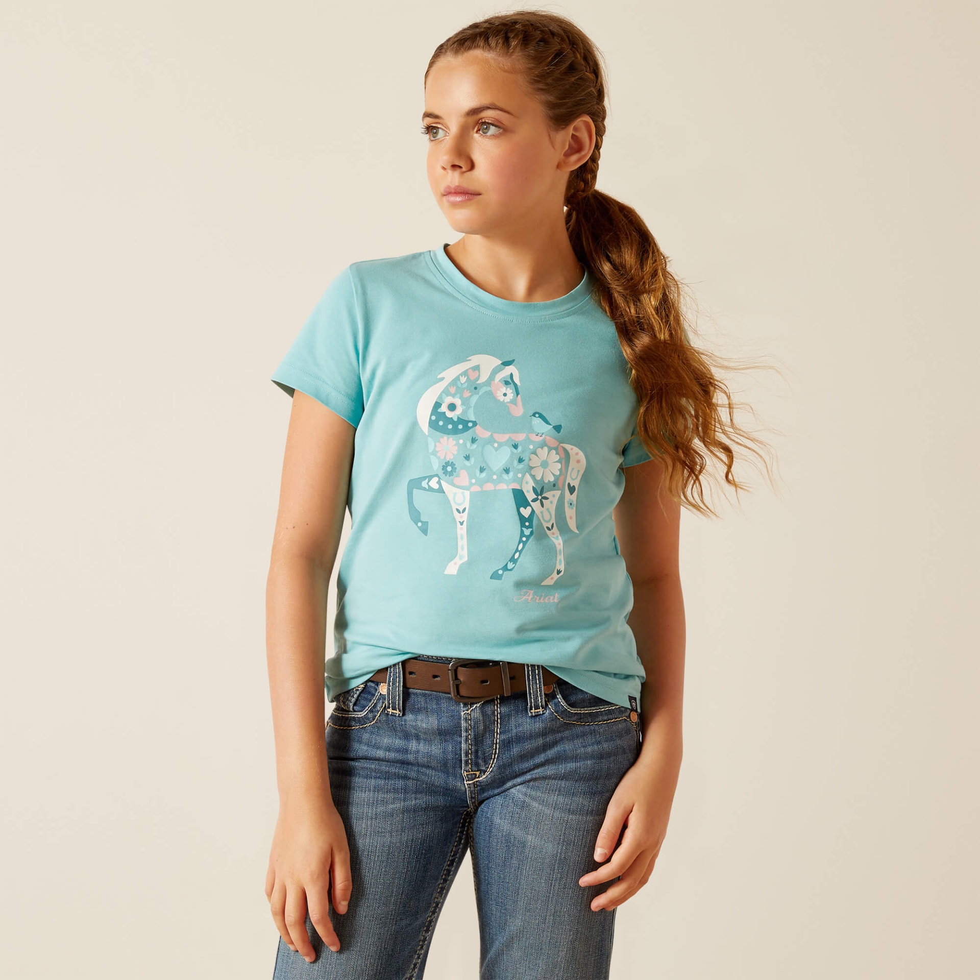 T-Shirt de Criança ARIAT "Little Friend" SS24 Menina a usar uma camiseta azul clara com estampa de cavalo e jeans.