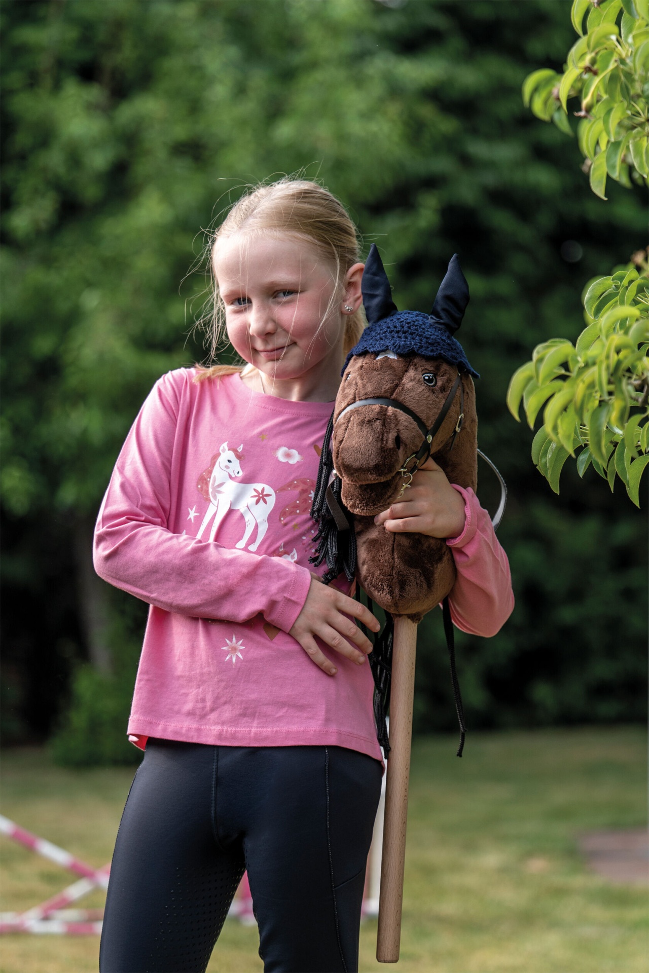 Orelheiras Hobby Horsing HKM Criança segurando cavalo de peluche castanho no jardim.