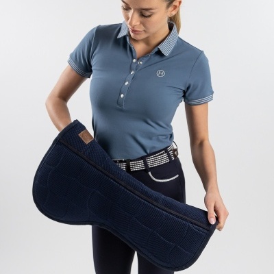 Mulher com polo azul e calças escuras a segurar manta azul escura acolchoada