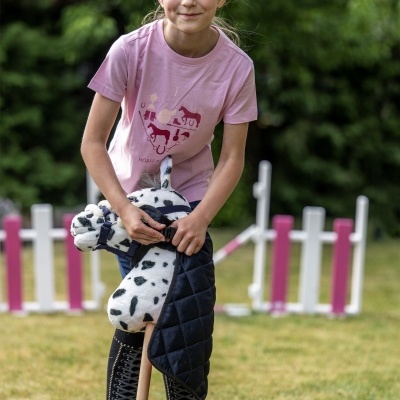 Menina com camisola rosa e cavalo de pau em campo de hipismo