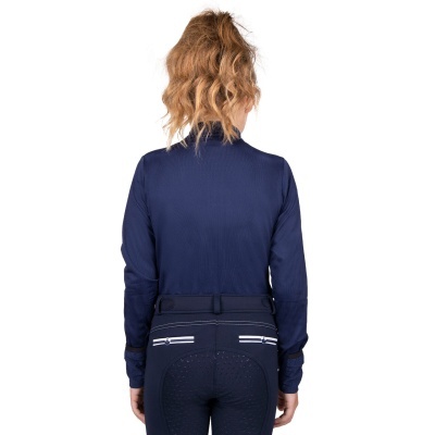 Mulher com camisa azul escuro e calças de equitação pretas com detalhes brancos