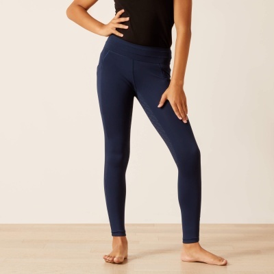 Leggings azuis escuras usadas por modelo com t-shirt preta, em interior com chão de madeira