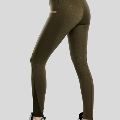 Calças justas desportivas verde-oliva com textura perfurada e ténis cinzentos e vermelhos.