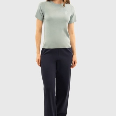 Mulher de pé com t-shirt verde-acinzentada e calças pretas largas