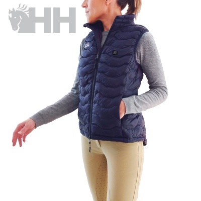 Colete azul escuro acolchoado com fecho, usado por mulher com camisola cinzenta e calças bege