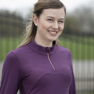 Blusa roxa de manga comprida com fecho dourado e textura frontal em modelo ao ar livre