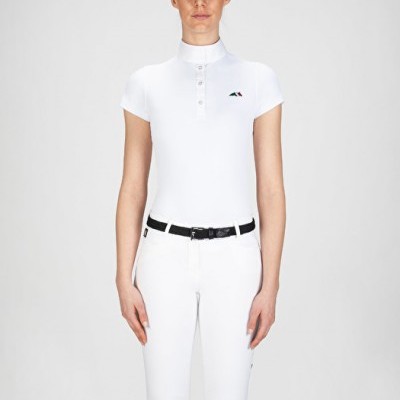 Mulher com camisa branca de manga curta e calças brancas ajustadas com cinto preto e botas pretas