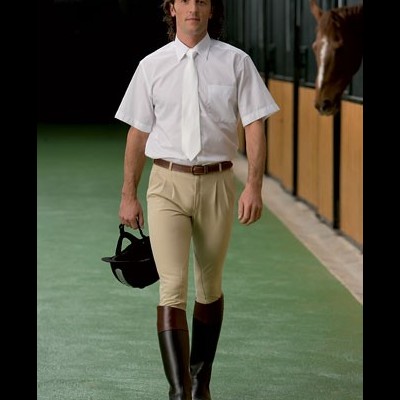 Homem a usar roupa de equitação numa estrebaria com cavalo ao lado