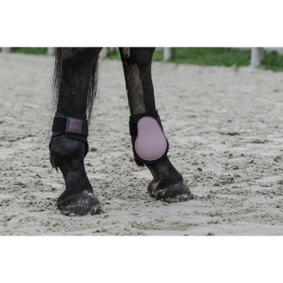 Patinhas de cavalo com proteções acolchoadas preto e rosa numa pista de areia