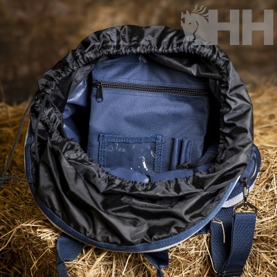 Mochila azul escura aberta com bolsos internos e revestimento preto, pendurada em feno