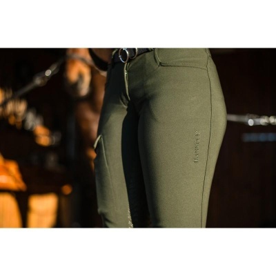Calças justas verde-oliva com inscrição HORSE PILOT em ambiente com cavalo.