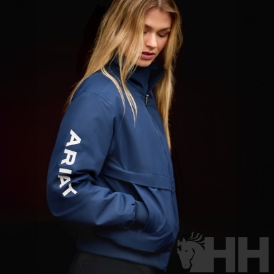 Casaco azul escuro com texto ARIAT na manga usado por mulher loira