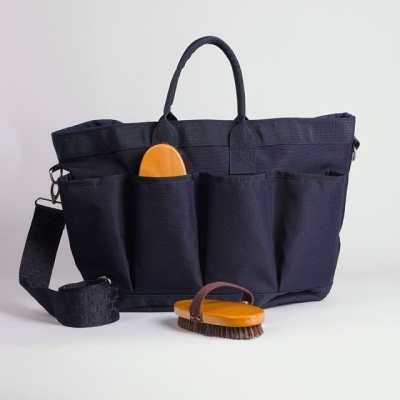 Mala preta com várias bolsas frontais e duas escovas em madeira e pêlo castanho.