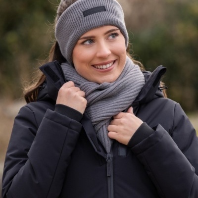 Mulher com casaco preto, cachecol cinzento e banda de cabeça cinzenta ao ar livre