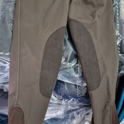 Calças castanhas com reforços escuros colocadas sobre saco plástico