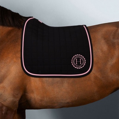 Sela de cavalo preta com bordas cor-de-rosa e logótipo H numa caveira castanha