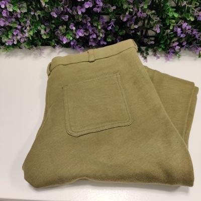 Calças verde caqui dobradas com bolso traseiro, fundo com flores roxas