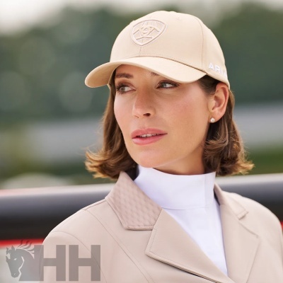 Boné bege com bordado frontal e mulher com casaco bege ao ar livre