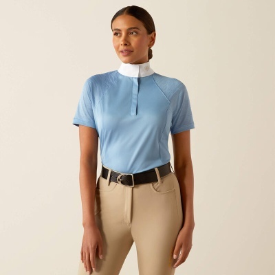 Mulher a vestir camisa azul clara de equitação com gola branca e calças bege