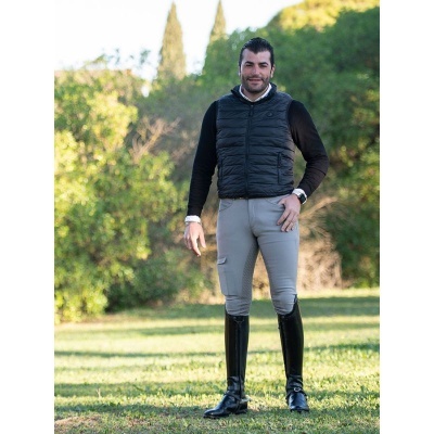 Homem com roupas de equitação numa relva verde com árvores ao fundo