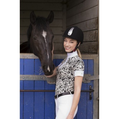 Mulher com roupa de equitação ao lado de cavalo preto num estábulo com porta azul