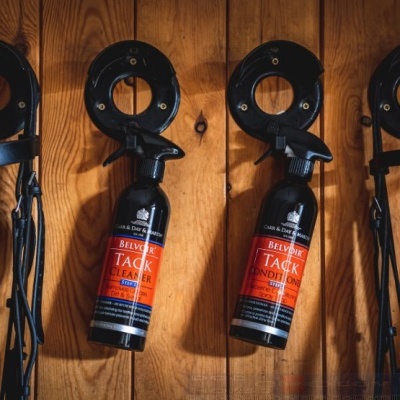 Garrafas de spray de limpeza e condicionamento Belvoir em suportes pretos contra fundo de madeira.