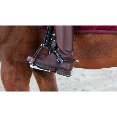 Bota de couro castanha em estribo metálico numa sela de cavalo