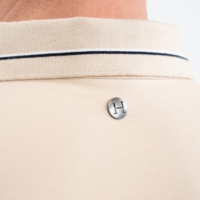 Polo bege com gola canelada e botão metálico com letra H na parte de trás