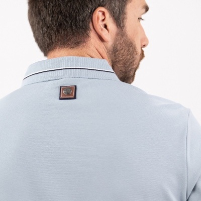 polo azul clara com etiqueta quadrada castanha nas costas