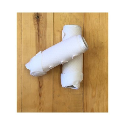 Dois protetores brancos acolchoados com fechos de velcro sobre madeira clara