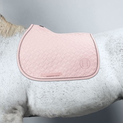 Alforge rosa acolchoado com padrão geométrico sobre cavalo branco
